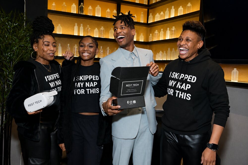Jon Batiste holding a Rest Tech VR headset box backstage at the Grammys