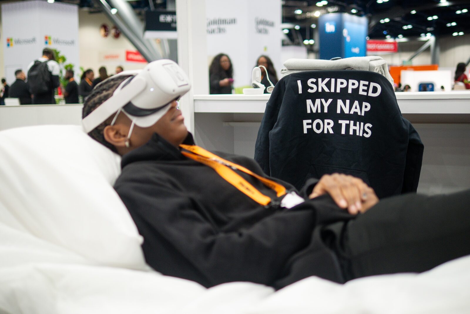 A participant lying back in a Rest Tech VR headset at a busy technology conference.